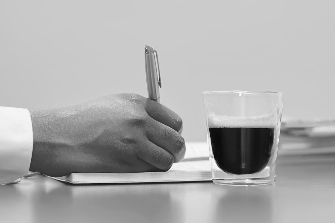 Hands reviewing a manuscript with a pen and coffee