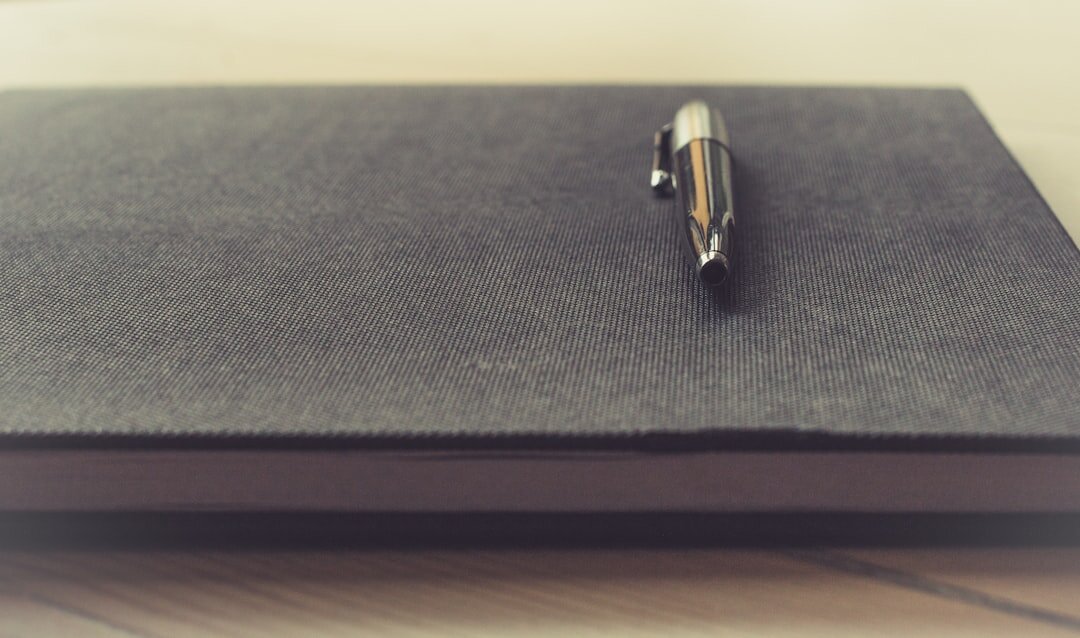 Fountain pen writing on a notepad next to a book